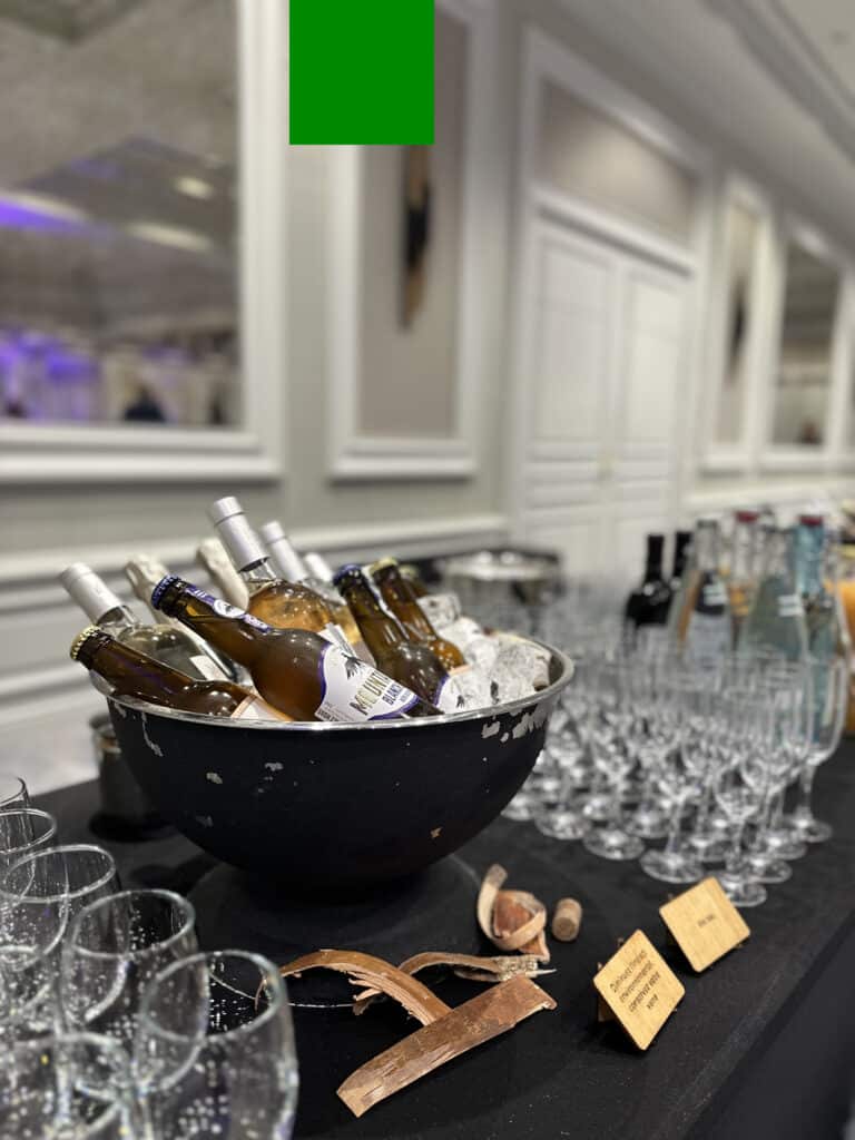 Buffet de boissons événementiel: bières, vins et verres à pied sur table noire. Panneau: «Diminuez l'impact environnemental, conservez votre verre».